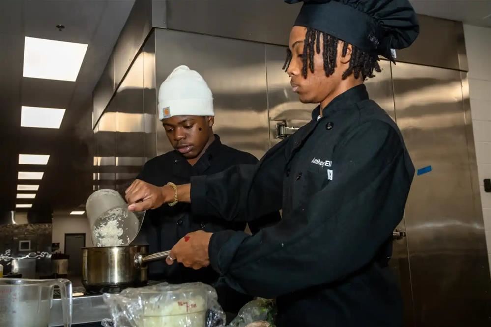 2 male students cooking rice