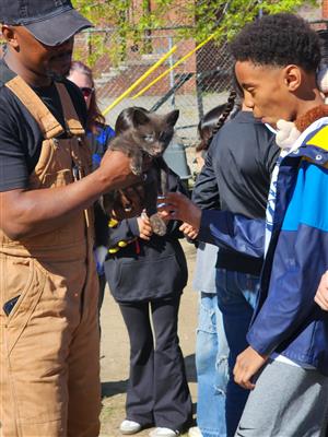 man holding an animal with a boy looking at it