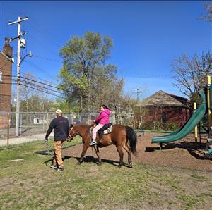 girl riding a horse and a man walking along =side them