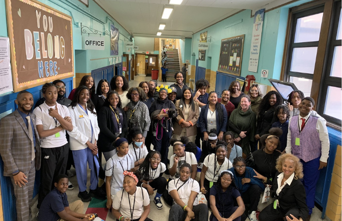  a large group of students, professionals, and teacher posing in hallway