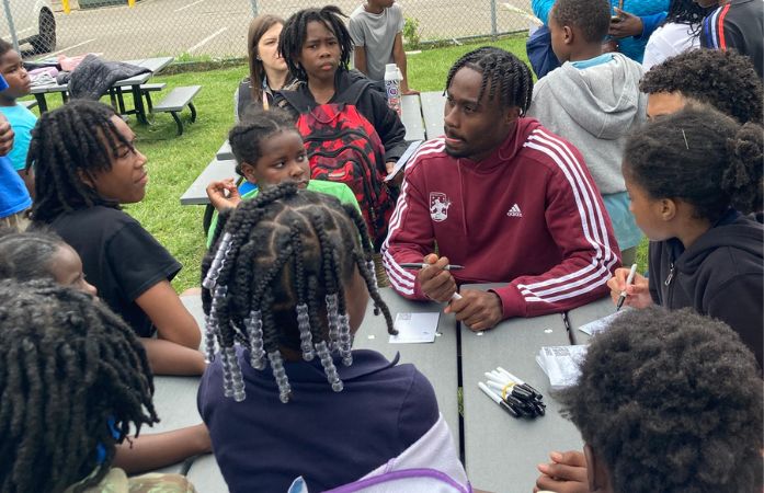  professional soccer player surrounded by students asking questions