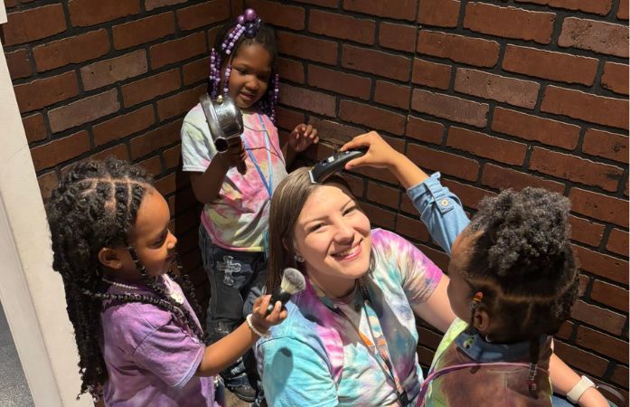  preschool students pretending to do their teachers hair and makeup