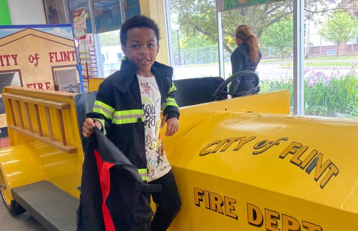  1st grade student dressed as a firefighter on fire truck