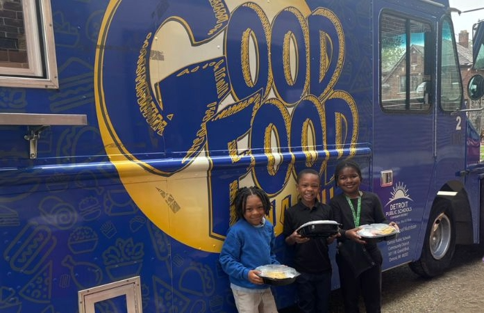  three first grade smiling students standing in front of food truck