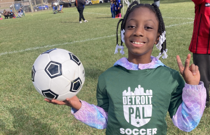 student smiling with soccer ball in hand