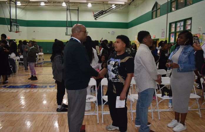  Students standing with parents to receive Eighth grade pin