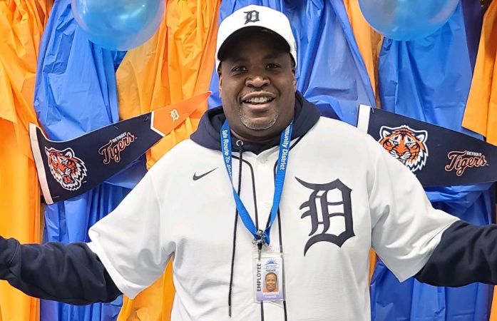  teacher smiling in front of tigers poster