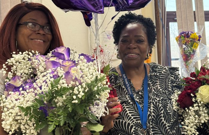  Ms. Henderson and Ms. Mitchell smiling holding flowers