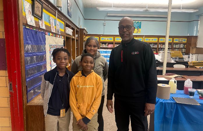  three students and a man standing in a library