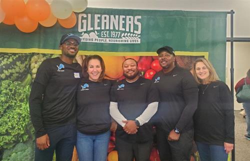  5 people from Detroit Lions Foundation standing in front of Gleaners banner