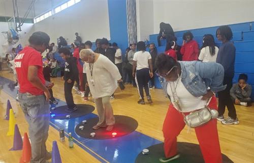 3 people stepping on lights with students standing in the background