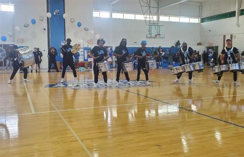 7 people with drums performing in the gym