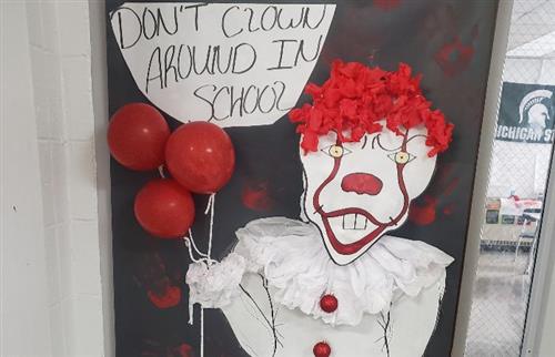  Door decorated with a white clown holding red ballons with sign saying Don't clown around in school
