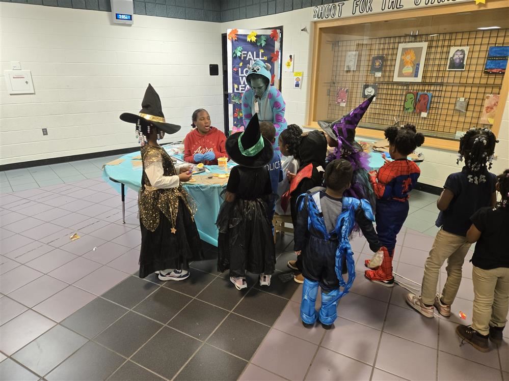  students in costumes getting treats from older students and teachers