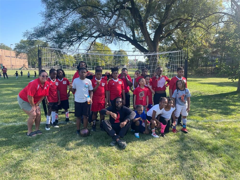  soccer players wearing red in front of a soccer goal.