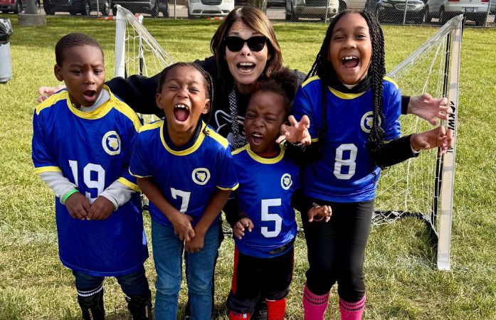 student athletes and a coach posing in a field.