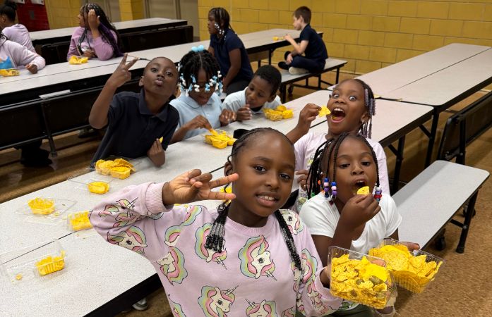  students sitting at a lunch table eating nachos.