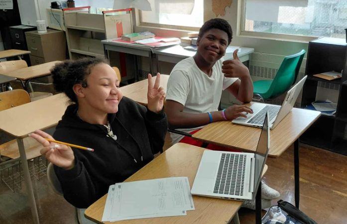  Male and female students posing for a picture while using their laptops