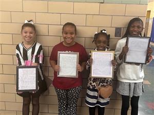  Four students posing with their framed essays