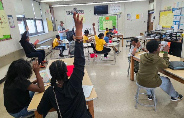  students with raised hands in a science classroom