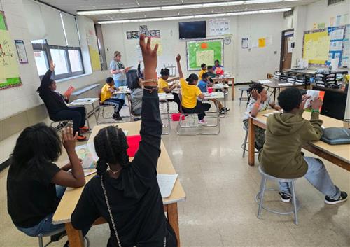 students with raised hands in a science classroom
