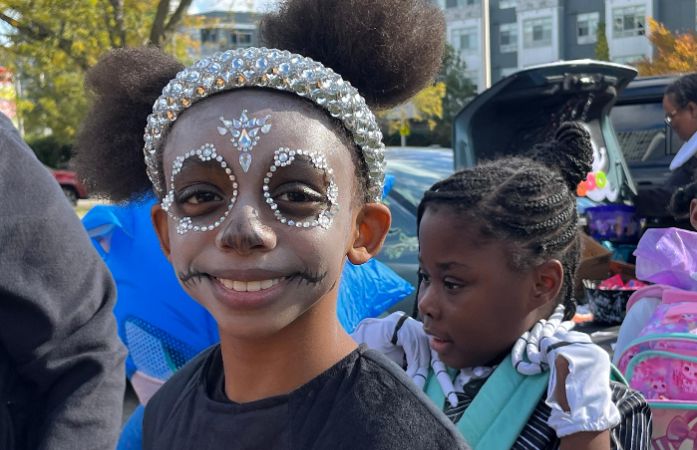  Close up of a student in a decorative skeleton costume smiling during Trunk or Treat