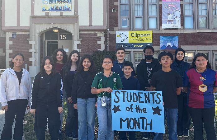  students smiling with a sign proclaiming them students of the month