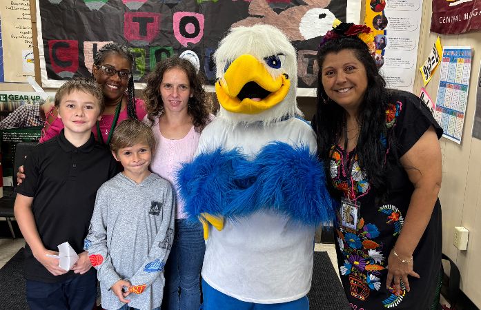a small group of smiling people with a eagle mascot