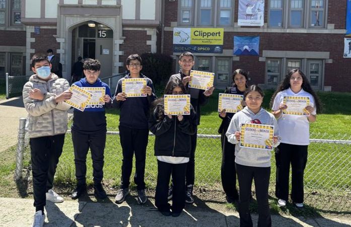  students standing in front of the building with their certificates