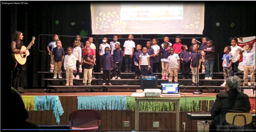 29 student performing while teacher plays guitar