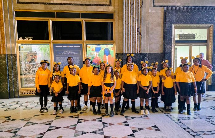  Girls standing with yellow tops and black bottoms.