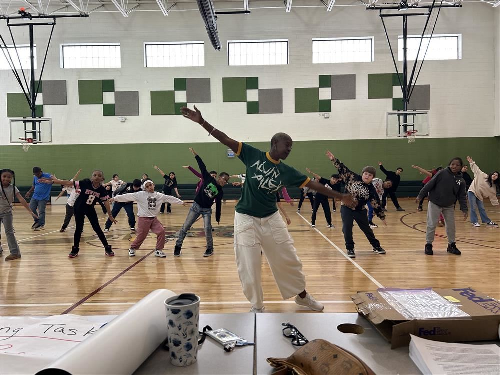  students and adults dancing in a gymnasium