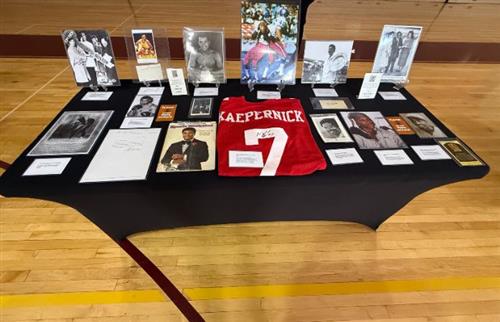 A black table with black history artifacts displayed, red football jersey 