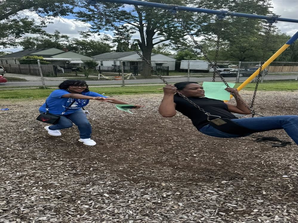  Female staff member pushing another on swing-set at school playground