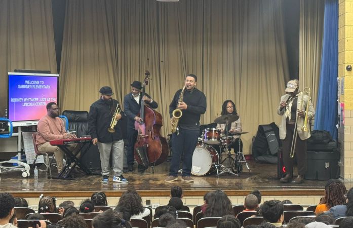band standing on stage while students watch