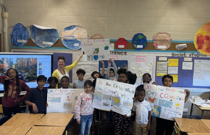 teacher and students holding completed inquiry product posters smiling