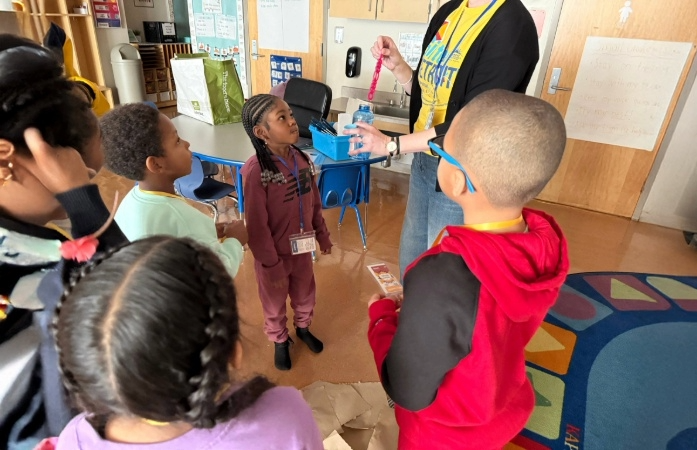  students standing in circle listening to presenter