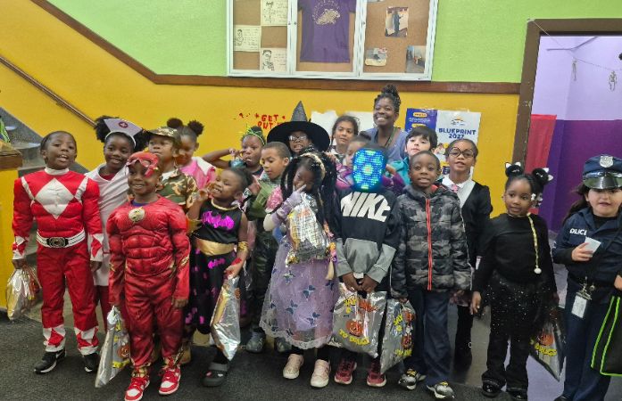  Teacher and her students in Halloween customs standing in the hallway 
