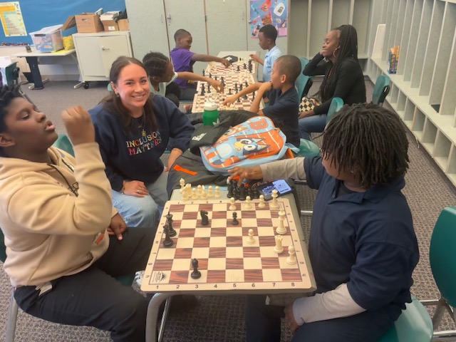  student and staff playing chess