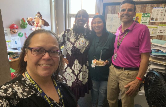  Picture of staff posing for picture while holding a slice of cake 